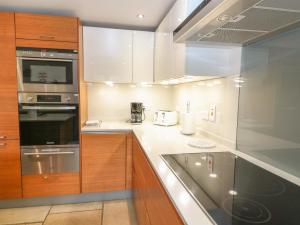 a kitchen with white counter tops and wooden cabinets at Malt Barn in Burford