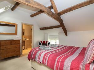 a bedroom with a red and white bed and a dresser at Malt Barn in Burford