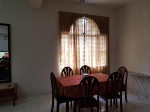 una sala da pranzo con tavolo, sedie e finestra di Homestay Melaka Bukit Beruang ad Ayer Keroh