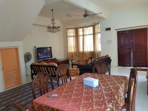 ein Wohnzimmer mit einem Tisch und Stühlen sowie ein Wohnzimmer in der Unterkunft Homestay Melaka Bukit Beruang in Ayer Keroh
