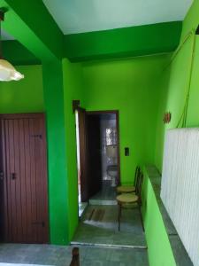 a green room with two chairs and a door at Double studio room by the sea in Tsagarada