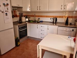 a kitchen with white cabinets and a white table in it at Pinares de Lepe in Huelva