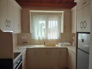a kitchen with white cabinets and a sink and a window at ΚΟΡΩΝΙΔΑ in Lygourio