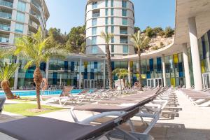 a row of lounge chairs in front of a building at Ágora Spa & Resort in Peñíscola