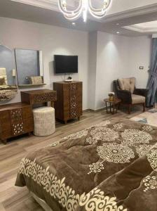 een slaapkamer met een bed, een tv en een stoel bij Jood Residences Apartment in Caïro