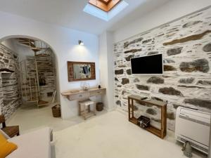 sala de estar con pared de piedra y TV en Captain's Port Studio, en Gavrion