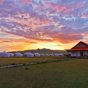 una puesta de sol con un grupo de tiendas blancas en un campo en Talbiun Lodge en Hujirt