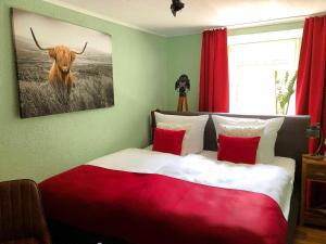 una camera con letto rosso e bianco e foto di un toro di Ferienhaus-Am-Alten-Stadttor a Ediger-Eller