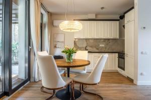 a kitchen with a wooden table and white chairs at Forest Cottage in Palanga