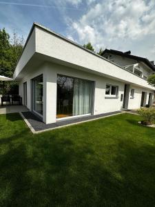 una casa bianca con un prato verde davanti di Moderne Ferienwohnung Rhenum mit Wallbox a Waldshut-Tiengen