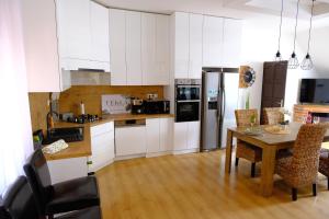 a kitchen with white cabinets and a table with chairs at Tekla apartman in Gyula