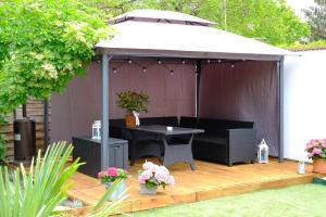 a gazebo with a table on a wooden deck at Tekla apartman in Gyula