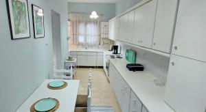a kitchen with white cabinets and green accents at Quiet House with Private Garden in Katerini