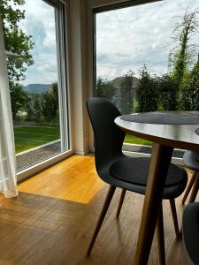 Zimmer mit einem Tisch und Stühlen sowie einem großen Fenster in der Unterkunft Moderne Ferienwohnung Rhenum mit Wallbox in Waldshut-Tiengen