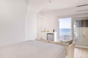 a white bedroom with a large bed and a view of the ocean at Afluencia Complex Studio No2 in Naousa