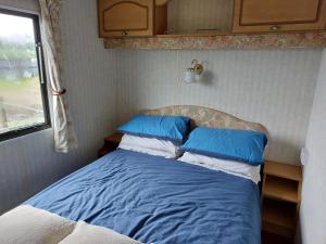 a bedroom with a bed with blue and white pillows at Braemar Equestrian, East Riding of Yorkshire in Burton Pidsea