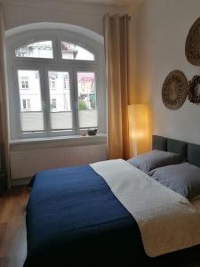 Un dormitorio con una cama azul y una ventana en Obszerne mieszkanie w centrum uzdrowiska z garażem en Świeradów-Zdrój