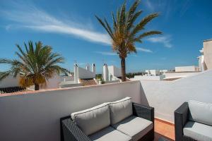 a patio with a couch and palm trees on a balcony at Beautiful and Quiet Family Townhouse in Great Location in Marbella