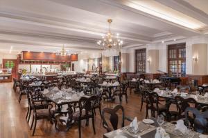 a dining room with tables and chairs and a chandelier at The Grand Hotel - Heritage Grand in Nuwara Eliya