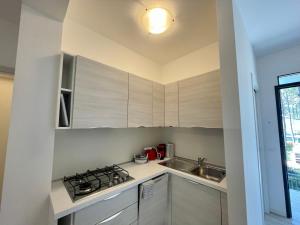 a kitchen with white cabinets and a sink and a stove at Villa Antonietta 3, tra pineta e mare in Bibione