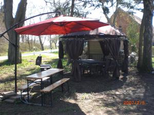 a tent with a bench and a red umbrella at gramelower see in Teschendorf