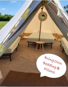 a tent with a chair and a sign that says flying only releasing pillows at Dorset Glamping Fields in Corfe Mullen