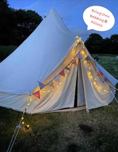 a white tent with lights in a field at Dorset Glamping Fields in Corfe Mullen