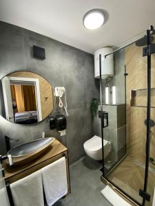 a bathroom with a sink and a toilet and a mirror at 4 Rooms Apartments in Niš