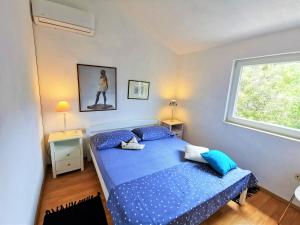 a bedroom with a bed with blue sheets and a window at Holiday Home Villa Marela in Drvenik Veli