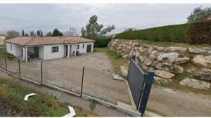 a fence in front of a house with a stone wall at Villa- suite privée avec accès sur piscine 