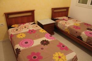 Dos camas en un dormitorio con flores. en LE JASMIN RESIDENCE bord de mer, en Hammam Sousse