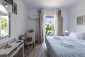 Schlafzimmer mit einem Bett, einem Schreibtisch und einem Fenster in der Unterkunft Hotel Manto in Naoussa