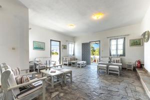 a living room with chairs and tables and windows at Hotel Manto in Naousa
