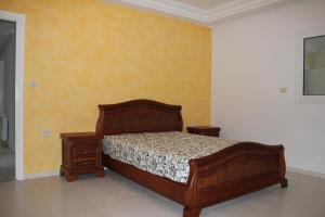 a bedroom with a wooden bed and two night stands at LE JASMIN RESIDENCE bord de mer in Hammam Sousse
