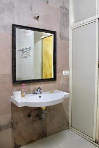 W łazience znajduje się umywalka i lustro. w obiekcie Royal Phoenix Inn w mieście Panaji
