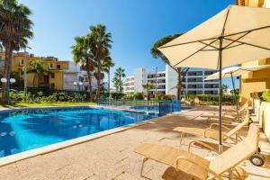 a swimming pool with chairs and an umbrella at Apartamentos Rio by Garvetur in Vilamoura