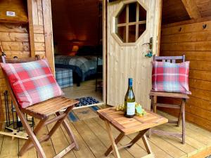 um quarto com duas cadeiras e uma garrafa de vinho em Seal Cove Cabin - Luxury Glamping em Cairndow