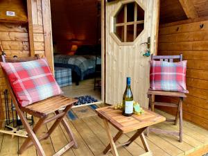 a room with two chairs and a bottle of wine at Seal Cove Cabin - Luxury Glamping in Cairndow