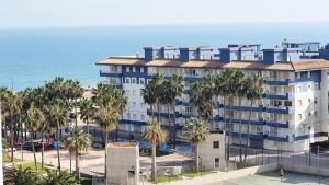 a building with palm trees in front of the ocean at EUROPA I - Playa de Miramar in Miramar