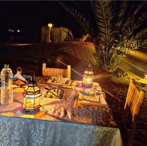 a table with some lights on it on a beach at night at Krich Camp in Merzouga