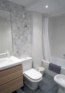 Baño blanco con aseo y lavamanos en Preciosos apartamentos Riojaland en Lardero, en Lardero