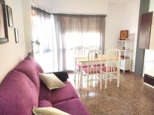 a living room with a purple couch and a table and chairs at Apartamento con vistas al castillo in Sagunto