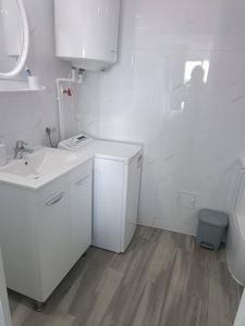 La salle de bains blanche est pourvue d'un lavabo et de toilettes. dans l'établissement Olimp sea view, à Olimp