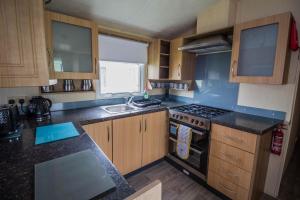 a kitchen with wooden cabinets and a stove top oven at 8 Berth Caravan For Hire Near Clacton-on-sea In Essex Ref 26287e in Clacton-on-Sea