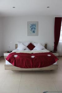 una camera da letto con un grande letto con una coperta rossa di Bodensee Pension a Überlingen