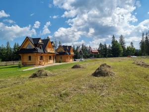 une maison en rondins dans un champ avec du foin dans l'établissement Chałupy Góralskie, à Witów