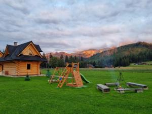 - une aire de jeux dans un champ avec une maison dans l'établissement Chałupy Góralskie, à Witów