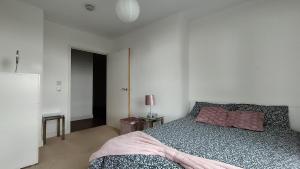 ein Schlafzimmer mit einem Bett in einem weißen Zimmer in der Unterkunft Riverview Amazing 2Bed 2Bath Apt wParking Sleeps 6 Comfortably in London