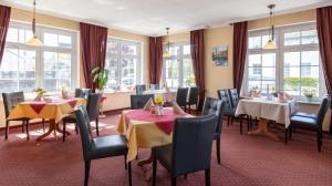 a dining room with tables and chairs and windows at Hotel am Wariner See in Warin