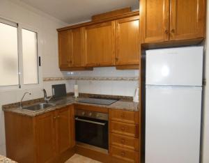 - une cuisine avec des placards en bois et un réfrigérateur blanc dans l'établissement City Comfort, Your Torrevieja Retreat, à Torrevieja